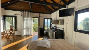 a room with a bed and a kitchen with a table at NOVIDADE - Cabana Refúgio Gaia in Annitapolis