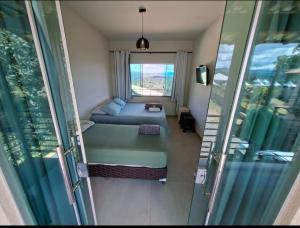 a small room with a bed and a window at Chalé Alta Vista Acuruí in Itabirito