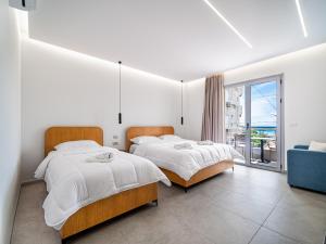 two beds in a white room with a window at Vourtaréa Guesthouse in Himare