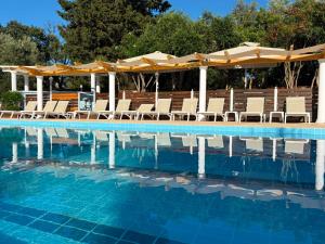 a swimming pool with lounge chairs and umbrellas at KATIA BEACH Holiday Cottage in Kassiopi