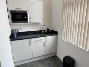 a white kitchen with a sink and a microwave at Fishergate Residences in Preston