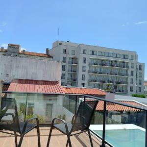 a balcony with two chairs and a large building at Santa Alegria Hostel in Ponta Delgada