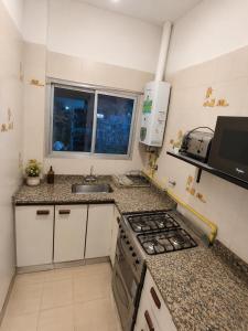 a small kitchen with a stove and a sink at La Casa de Miel in Villa Ballester