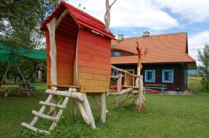 a red play house with a slide in a yard at Apartmánová chalupa v Dvore u maliara in Bešeňová