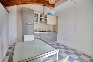 a kitchen with a glass table and chairs at Mansarda Canarina in Marina di Pescoluse