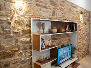 a room with a stone wall with a tv on a shelf at Meltemi Apartment in Chios