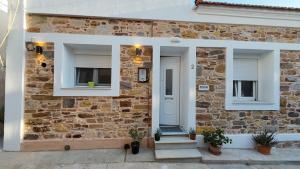 a stone house with a white door and windows at Meltemi Apartment in Chios