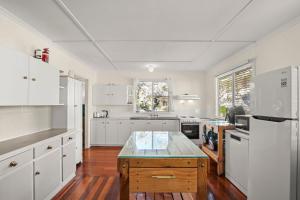 a kitchen with white cabinets and a table in it at Kitchener Street 2, Golden Beach in Golden Beach