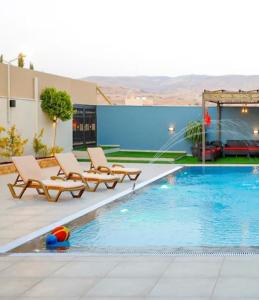 a pool with two lounge chairs next to a building at The Mountain View in Ash Shāghūr