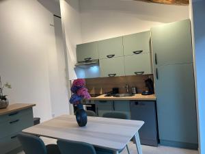 a kitchen with a table with a vase with flowers on it at Gîte Alice Piscine privée in Hauterives