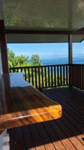 a wooden bed on a deck with a view of the ocean at Bungalow Omati in Tahateao +8 photos