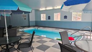 a pool with a table and chairs and an umbrella at Roosevelt Inn Mount Rushmore in Keystone