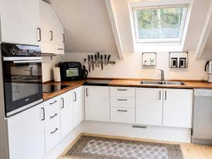 a kitchen with white cabinets and a sink and a window at Bright Cottage with Hot Tub in Ebeltoft