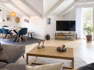 a living room with a tv and a table at Bright Cottage with Hot Tub in Ebeltoft
