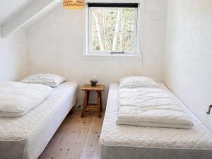 two beds in a room with a window at Bright Cottage with Hot Tub in Ebeltoft