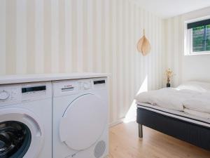 a white laundry room with a washer and a bed at 5 star holiday home in Kolding in Kolding