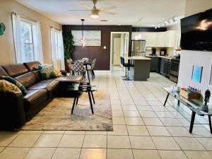 a living room with a brown couch and a kitchen at Sunshine Acre 2B 2B King Master Suite, BIG Yard in Davie