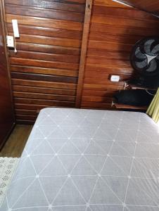 a room with a bed with a wooden wall at pousada nosso cantinho in Paranaguá