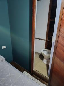 a bathroom with a toilet through a glass door at pousada nosso cantinho in Paranaguá