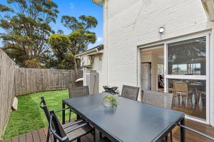 a patio with a table and chairs in a backyard at Mariners in the Village in Shellharbour +1 photo