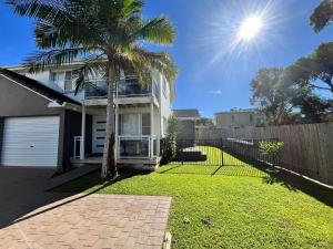 a house with a palm tree in the yard at Mariners in the Village in Shellharbour