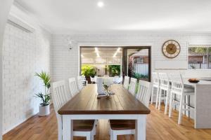 a dining room with a wooden table and white chairs at Southcoast Haven in Shoalhaven Heads +18 photos