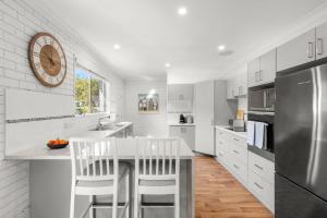 a kitchen with white cabinets and a counter with bar stools at Southcoast Haven in Shoalhaven Heads
