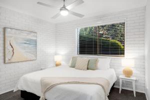 a white bedroom with a bed and a window at Southcoast Haven in Shoalhaven Heads