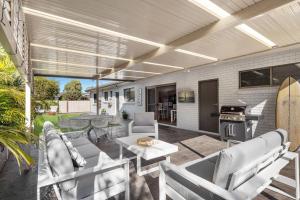 a patio with chairs and a table and a grill at Southcoast Haven in Shoalhaven Heads