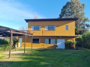 a yellow house with a yard in front of it at El Encuentro in Sierra de los Padres +5 photos