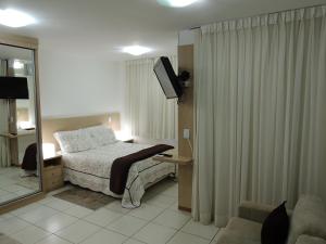 um quarto com uma cama, um espelho e uma televisão em Life Resort em Brasília