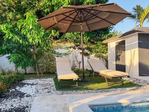 two chairs and an umbrella next to a pool at Villa La Dueña Las Terrenas in Las Terrenas
