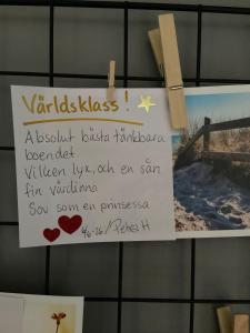 a sign hanging on a bathroom wall with a letter at Bollnäs Lugn och Ro in Bollnäs