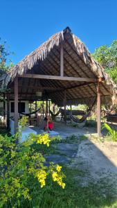 a pavilion with a hammock and a child sitting under it at Bicho Grilo Hostel in Atins