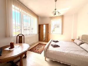 a bedroom with a bed and a table and windows at Mountain View House Busteni in Buşteni