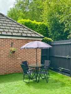 a table and chairs with an umbrella in a yard at New Haven Atherton Greater Manchester in Atherton