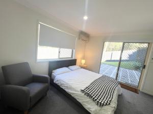 a bedroom with a bed and a chair and a window at Forest view guesthouse in Runcorn