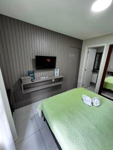 a bedroom with a green bed and a flat screen tv at VG Cumbuco J&Y in Caucaia
