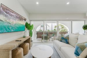 a living room with a white couch and a tv at The Reserve - Boca Designer Pool Suite in Boca Raton