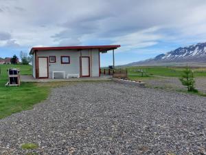 a small red and white building with a mountain in the background at Ásbrandsstadir Cottages in Vopnafjörður