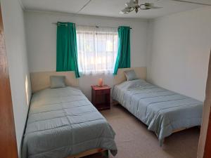 two beds in a room with green curtains and a window at Geranio Bed & Breakfast in Casablanca