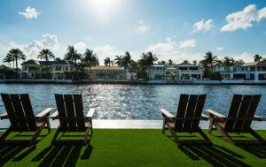 three chairs sitting in front of a lake with houses at The Reserve - Boca Designer Pool Suite in Boca Raton