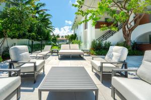a row of lounge chairs and tables on a patio at The Reserve - Boca Designer Pool Suite in Boca Raton