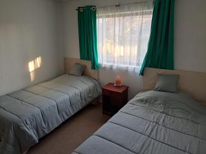 two beds in a room with green curtains and a window at Geranio Bed & Breakfast in Casablanca