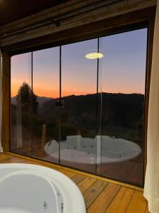 a bath tub in a room with a large window at Chalé Pazinato in Venda Nova do Imigrante