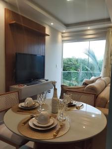 a living room with a table and a television at 05 minutos da praia - Casa Superior céu azul Buzios in Búzios