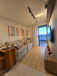 a living room with a couch and a tv at Vista Mar Icaraí Ingá in Niterói
