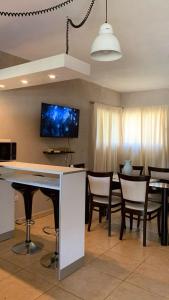 a living room with a bar with chairs and a tv at La Casita de la Granja, Casa con Pileta Y Gran Parque in La Granja
