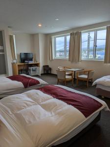 a hotel room with two beds and a table and chairs at Fuji Mountain Resort Hotel in Fujikawaguchiko