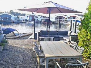 a wooden table and chairs with a couch and an umbrella at Aquaronde 108 in Lemmer